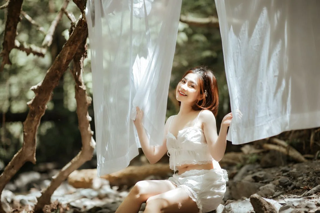 Woman holding white linen fabric while seated outdoors